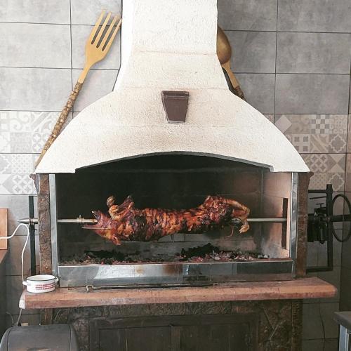 a roast chicken cooking in an outdoor oven at Imanje sa bazenom in Obrenovac