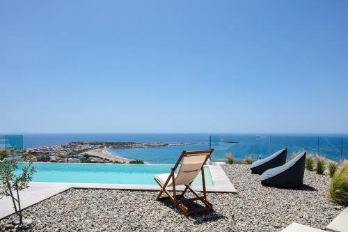 a chair and a lounge chair next to a swimming pool at Krystallon Villas in Palaiochora