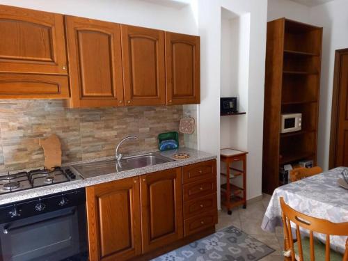 cocina con armarios de madera, fregadero y fogones en Domus Shardana en Gonnesa