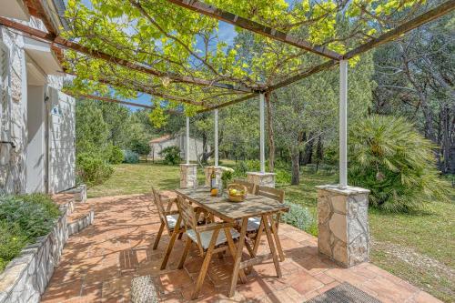 a wooden table and chairs on a patio with a pergola at Eco House Zabodarski Beach - Happy Rentals in Čunski