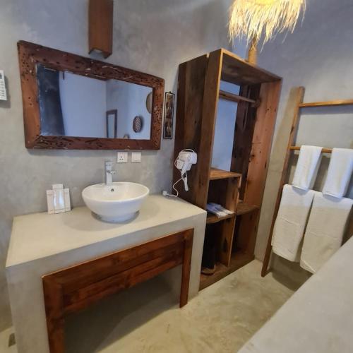 a bathroom with a sink and a mirror and towels at Mambo Cabana in Pwani Mchangani