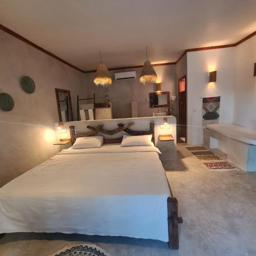 a bedroom with a large white bed in a room at Mambo Cabana in Pwani Mchangani