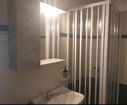 een badkamer met een wastafel en een douche met een spiegel bij Meltemi in Posidhonía