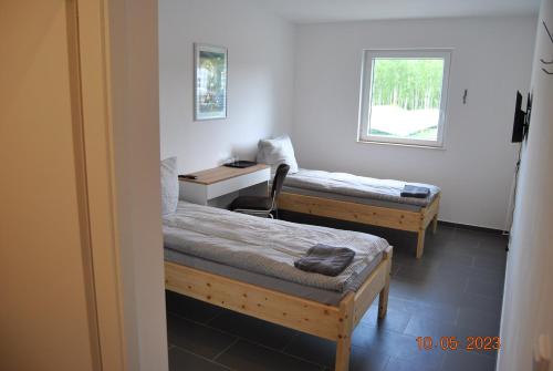 EberswaldeにあるZimmervermietung Eberswaldeのベッド2台、デスク、窓が備わる客室です。