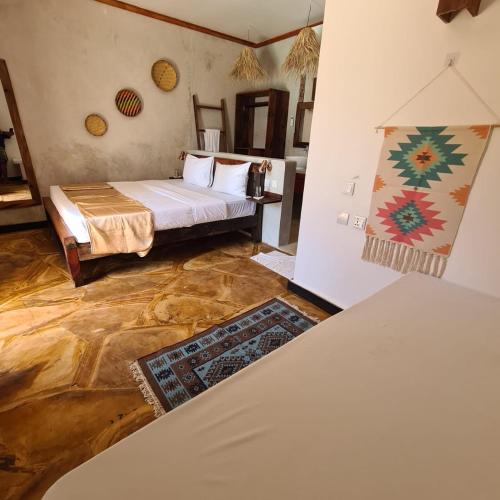 a room with a bed and a painting on the wall at Mambo Cabana in Pwani Mchangani