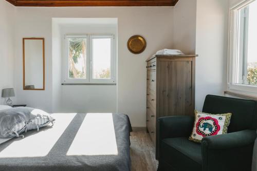 um quarto com uma cama, uma cadeira e janelas em Bird House em Lourinhã