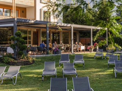 a group of chairs sitting in the grass in front of a building at Hotel SeeRose in Bodensdorf