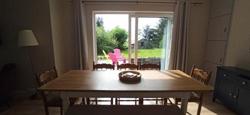 a dining room table with a pink chair in front of a window at Atlantic Way Cottage in Galway