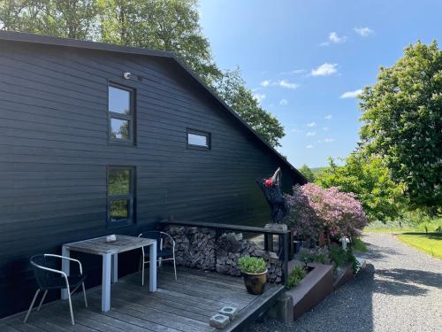a black house with a table and chairs on a deck at Skovlandshuset in Hadsten Stationsby