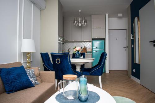 Apartamenty Kujawskie في تشيخوتشينيك: غرفة معيشة ومطبخ مع كراسي زرقاء وطاولة