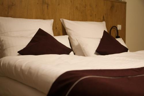 a bed with white sheets and black pillows at Ferienwohnung "Landhaus Buchenallee" in Bad Bentheim