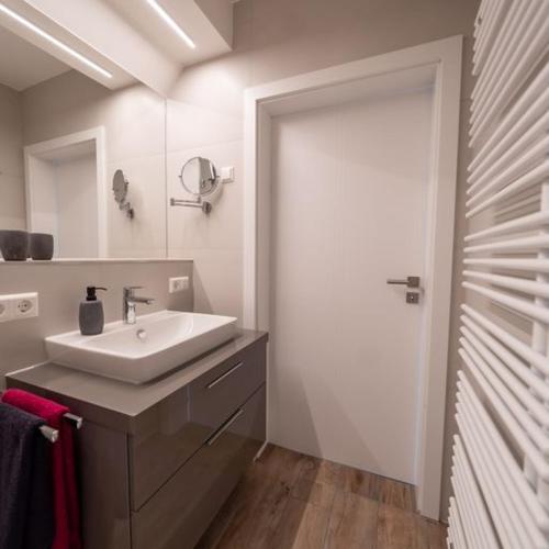 a white bathroom with a sink and a mirror at Ferienwohnung "Landhaus Buchenallee" in Bad Bentheim