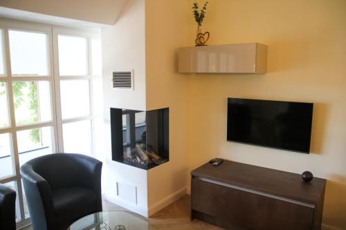 a living room with a tv and a chair and a table at Ferienwohnung "Landhaus Buchenallee" in Bad Bentheim