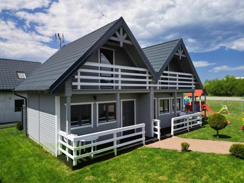 une maison avec un toit en gambrel et une aire de jeux dans l'établissement Domki i apartamenty Mila, à Sarbinowo