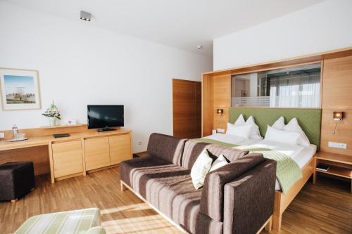 a hotel room with a bed and a couch at Hotel SeeRose in Bodensdorf