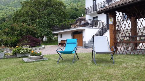 two chairs sitting in the grass in front of a house at Casa vacanze Fregè in Castione Andevenno