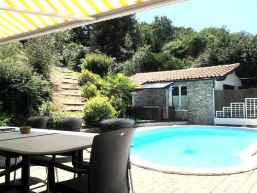 einen Pool mit einem Tisch und Stühlen sowie einem Tisch und einer Terrasse in der Unterkunft VILLA BIARRITZ PROCHE PLAGES in Biarritz