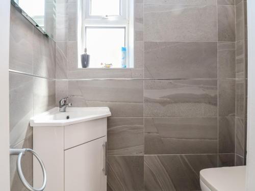 a bathroom with a sink and a toilet and a window at 11 Overdale Avenue in Wirral