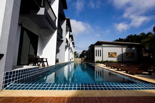 a swimming pool in front of a building at Alphabeto Resort in Nai Harn Beach