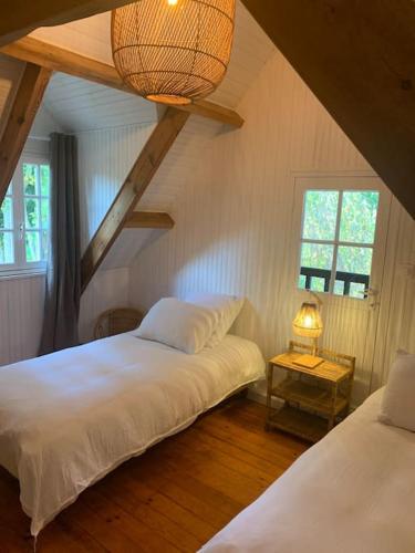une chambre avec deux lits et un lustre dans l'établissement Fermette La bergerie, à Cormont