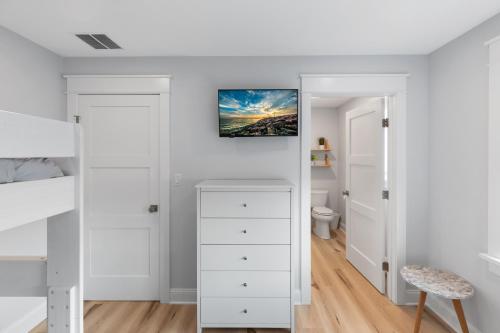 a bedroom with white walls and a white dresser at Cape May Ohana Beach Club in Cape May