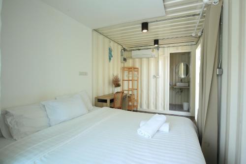 1 dormitorio con 1 cama blanca y 2 toallas en Day Off House Chiang Mai Near Walking Street en Chiang Mai