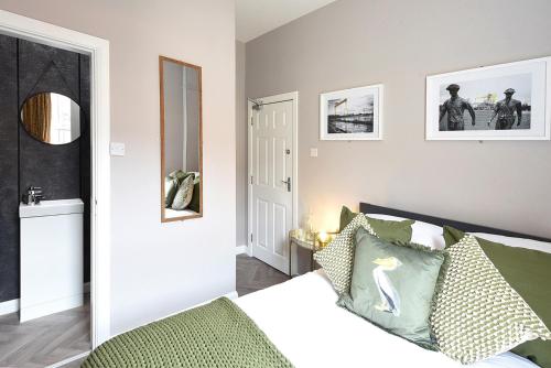 a bedroom with a bed with green pillows and a mirror at Ocho Homes by Eight Continents in Belfast