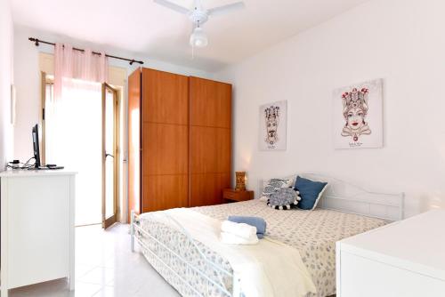 een witte slaapkamer met een bed en een plafondventilator bij ONDA MARINA in Agrigento