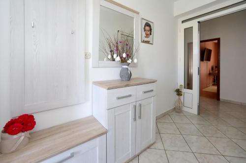 a kitchen with white cabinets and a vase of flowers at Apartments Adrian in Bibinje