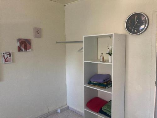 a white book shelf with a clock on a wall at SOFT YLaNG in Dembeni