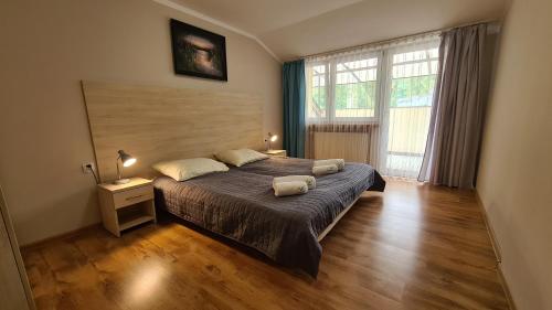 a bedroom with a large bed and a large window at Zacisze Natura Tour in Spała