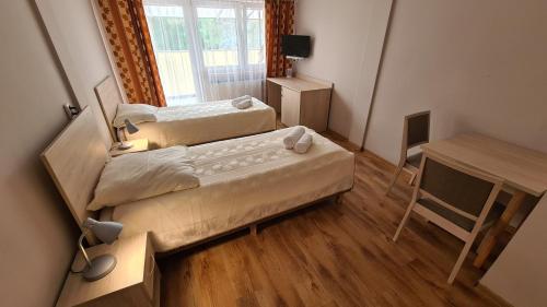 two beds in a small room with a desk and a desk at Zacisze Natura Tour in Spała
