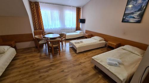 a room with two beds and a table and chairs at Zacisze Natura Tour in Spała