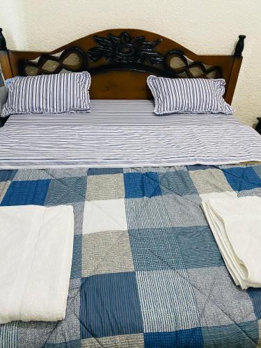 a bed with a checkered blanket and pillows on it at Virunga Homes in Ruhengeri
