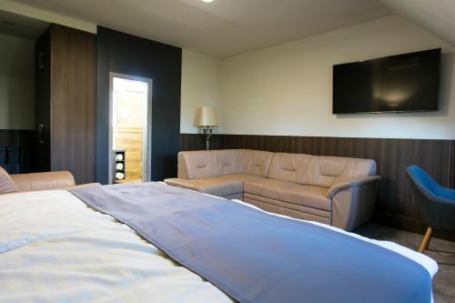 a bedroom with a bed and a couch and a tv at New York Pension in Dunajská Streda