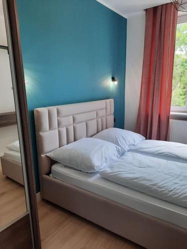 een slaapkamer met een bed met een blauwe muur en een raam bij Apartament z widokiem na Rynek Kościuszki in Białystok