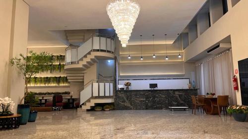 a lobby with a chandelier and a staircase in a building at Hotel Dan Inn Uberlandia in Uberlândia