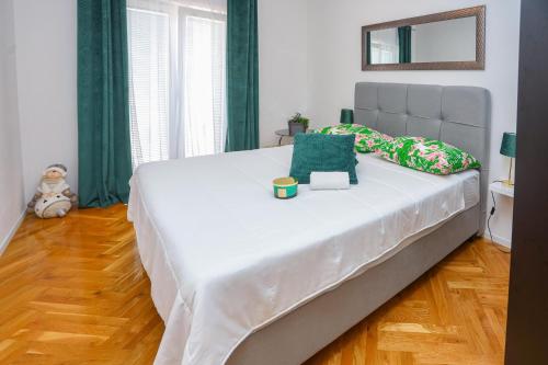 uma grande cama branca num quarto com cortinas verdes em Apartment Vesna near beach with the balcony em Podstrana