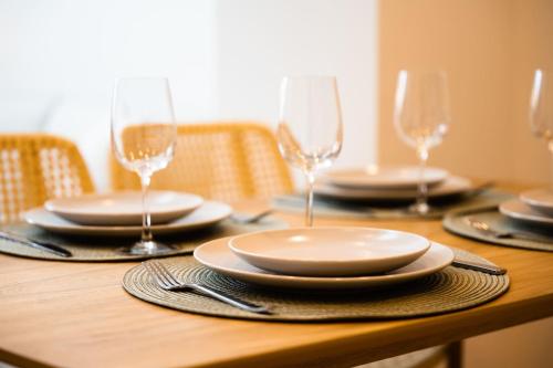 une table en bois avec des assiettes et des verres à vin dessus dans l'établissement Le Duplex Vaugelas atypique en plein Centre Ville, à Annecy