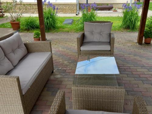 a patio with two chairs and a glass table at Napsugár Vendégház in Újudvar