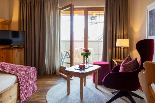 a hotel room with a bed and a table and chairs at Romantik Hotel Oberwirt in Marlengo