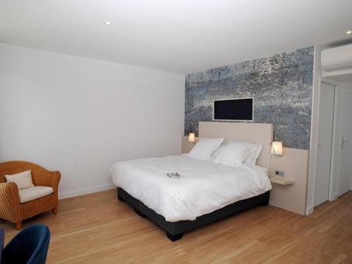 - une chambre avec un lit blanc et une chaise dans l'établissement Hôtel Les Mouettes, à La Couarde-sur-Mer