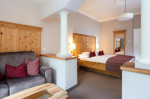 a hotel room with a bed and a couch at Romantik Hotel Oberwirt in Marlengo