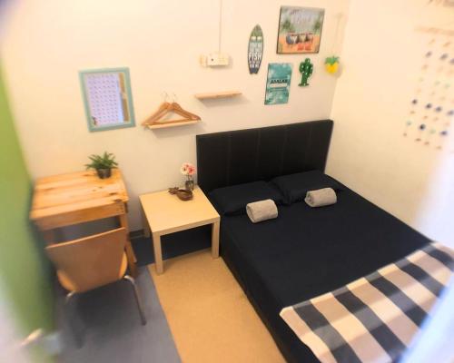 a small bedroom with a black bed and a desk at Lavender@Guesthouse in Melaka