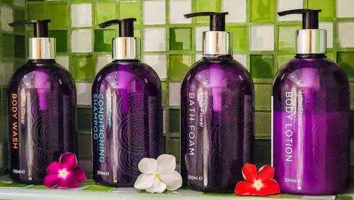 three purple bottles sitting on a shelf with flowers at Centara Muscat Hotel Oman in Muscat