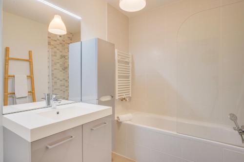 Les Flots - Appt 2 chambres près de la Cité du vin في بوردو: حمام أبيض مع حوض وحوض ومغسلة