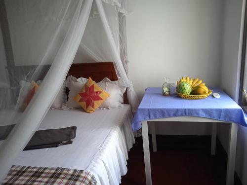 Un dormitorio con una cama y una mesa con un bol de fruta. en Sanaya Homestay, en Tangalle
