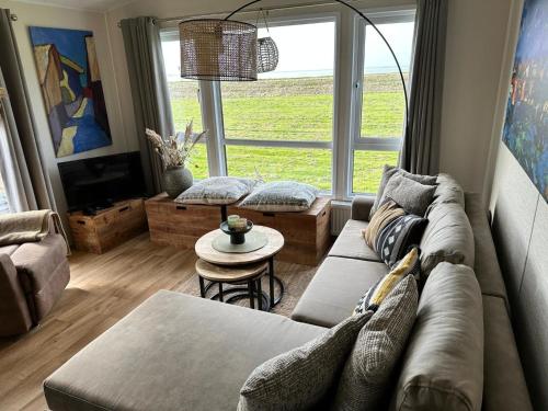 a living room with a couch and a table at Traumlage Meerblick Nr 26 Ferienhaus "Schau aufs Meer" erste Reihe unendliche Weite, eingebettet in der Natur in Westerland