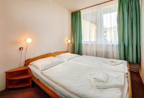 ein Schlafzimmer mit einem großen Bett mit grünen Vorhängen und einem Fenster in der Unterkunft Bungalovy FIS Economy in Štrbské Pleso