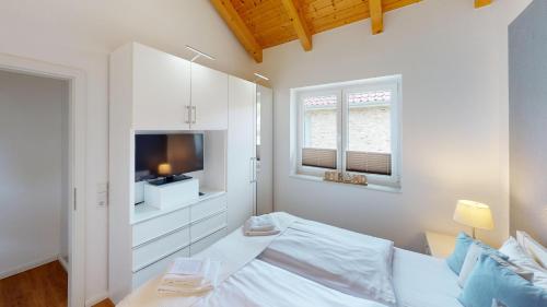 - une chambre blanche avec un lit et une télévision dans l'établissement Feriendorf Südstrand Haus 36, à Pelzerhaken